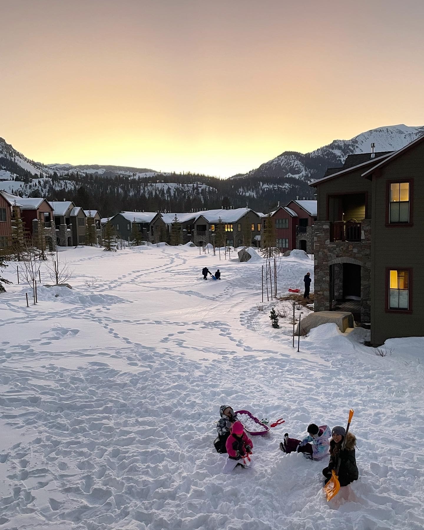 Snow covered hill at sunset with cabins