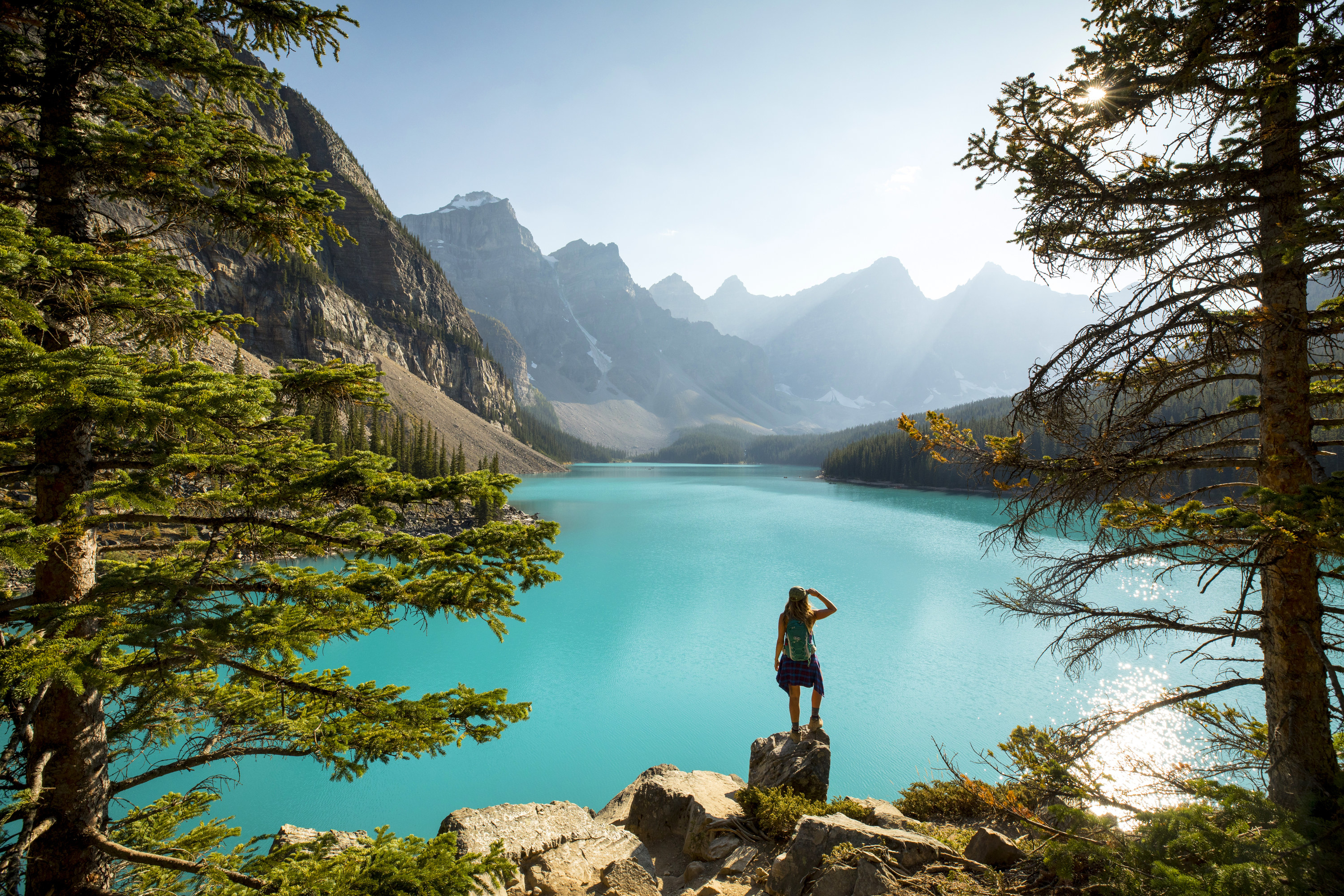 Person standing in front of a lake in front of mountains.