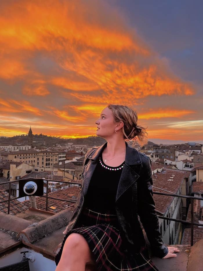 woman sitting in front of the view of houses in florence at sunset
