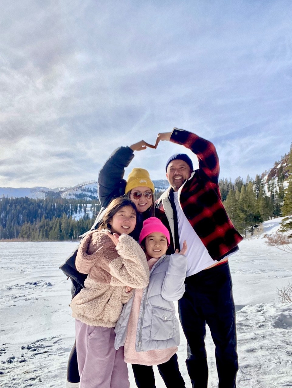 Family on a snowy mountain making a heart with their hands