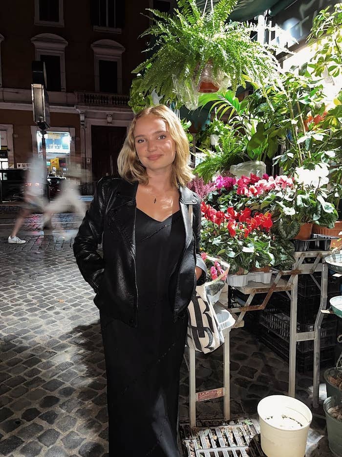 woman posing by flowers standing on cobblestones