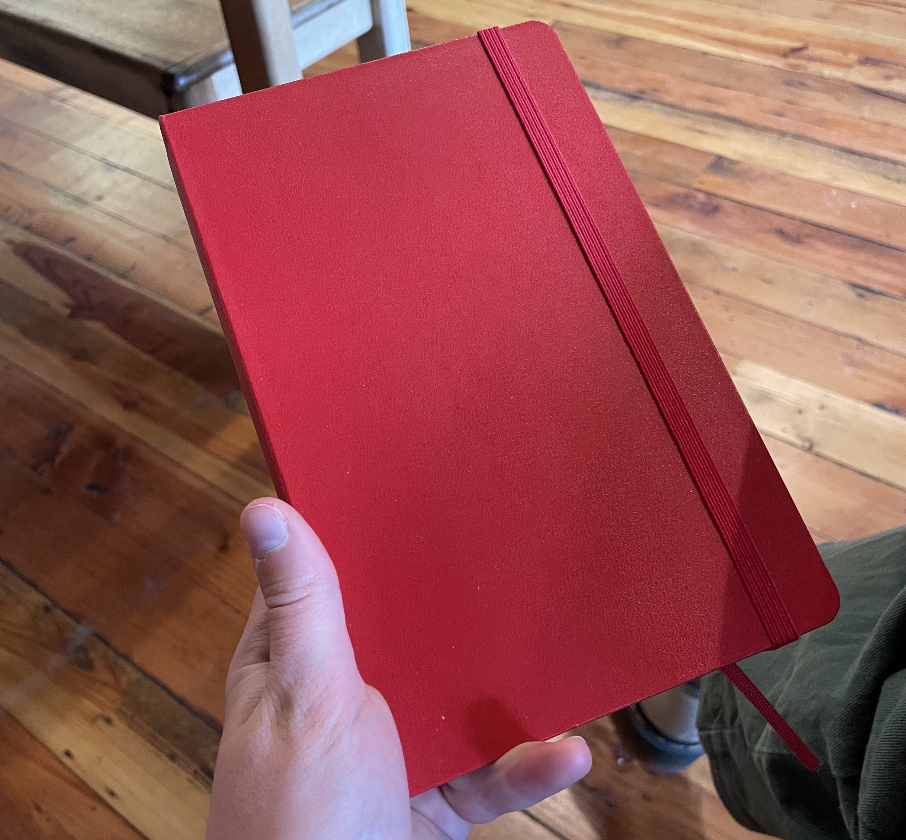 writer holding red notebook with elastic closure