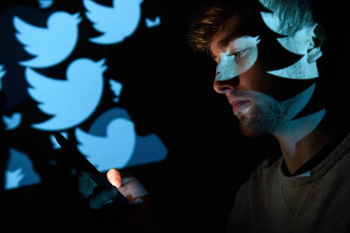 A person on their cellphone with Twitter logos in the background