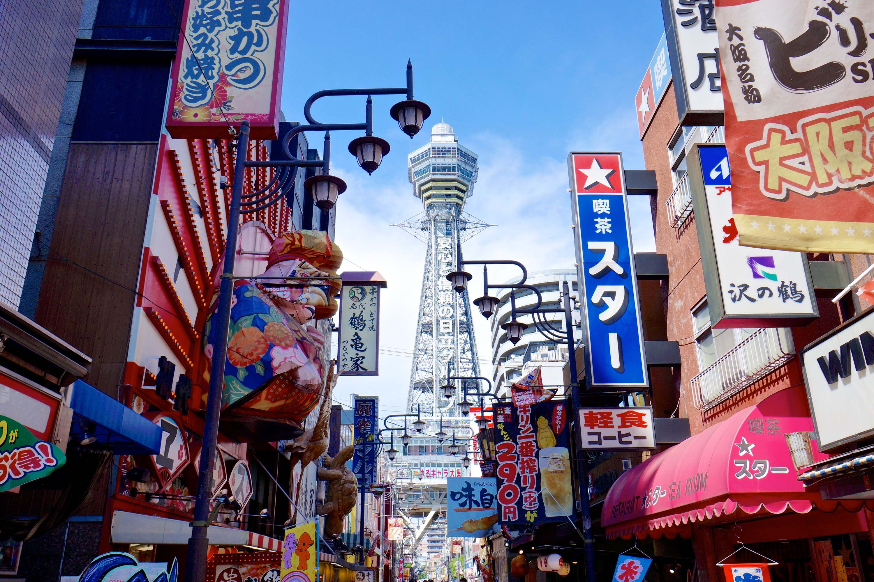 Colorful and showy signs of shops and restaurants against the backdrop of the Tsutenkaku tower
