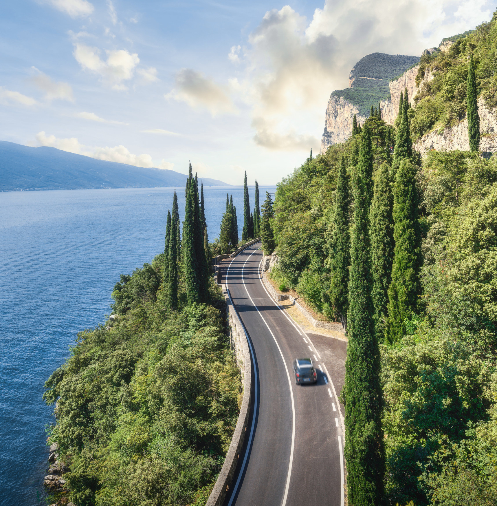 A car driving on a scenic road on Lake Garda.