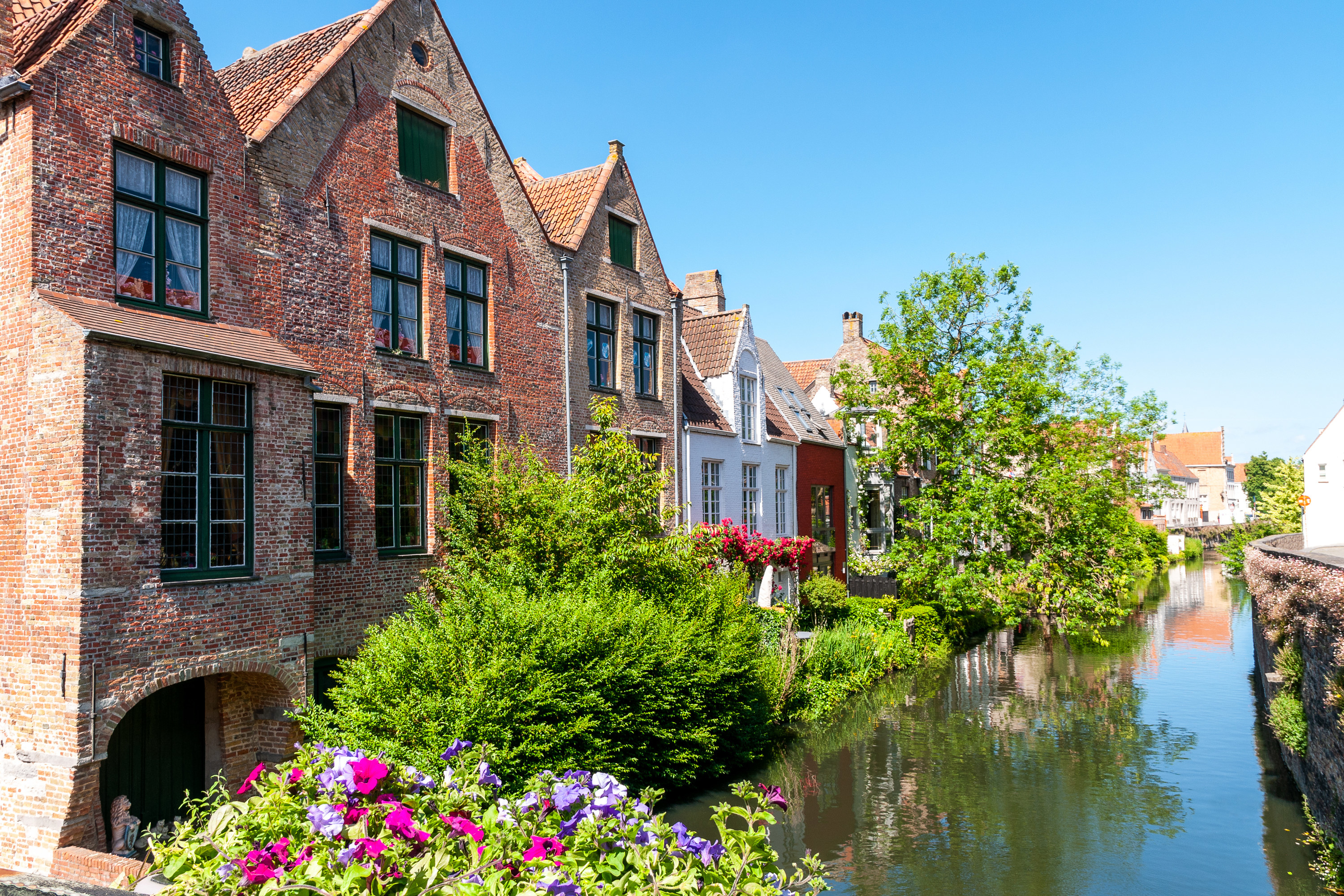 Old brick buildings beside a canal with flowers