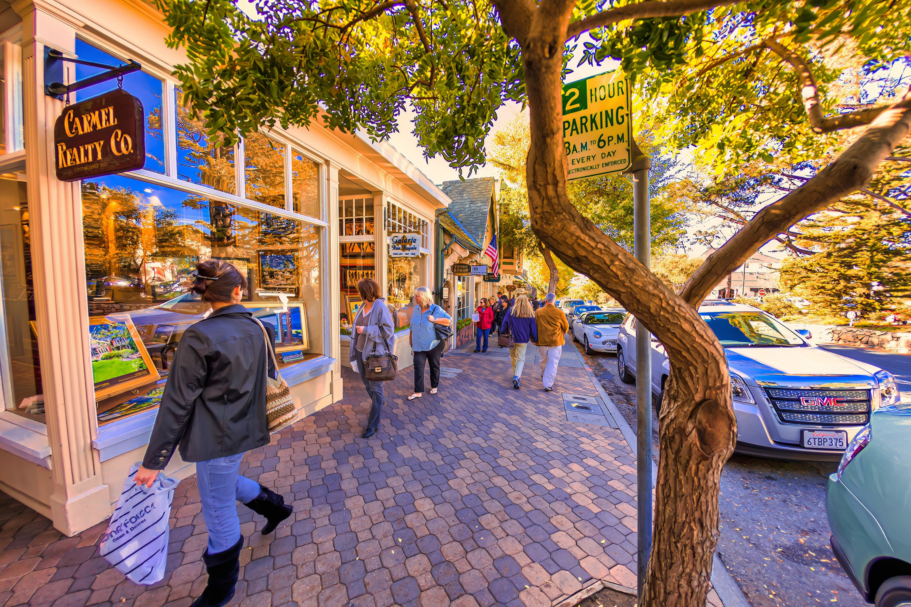 People walking down a cobblestone street lined with shops