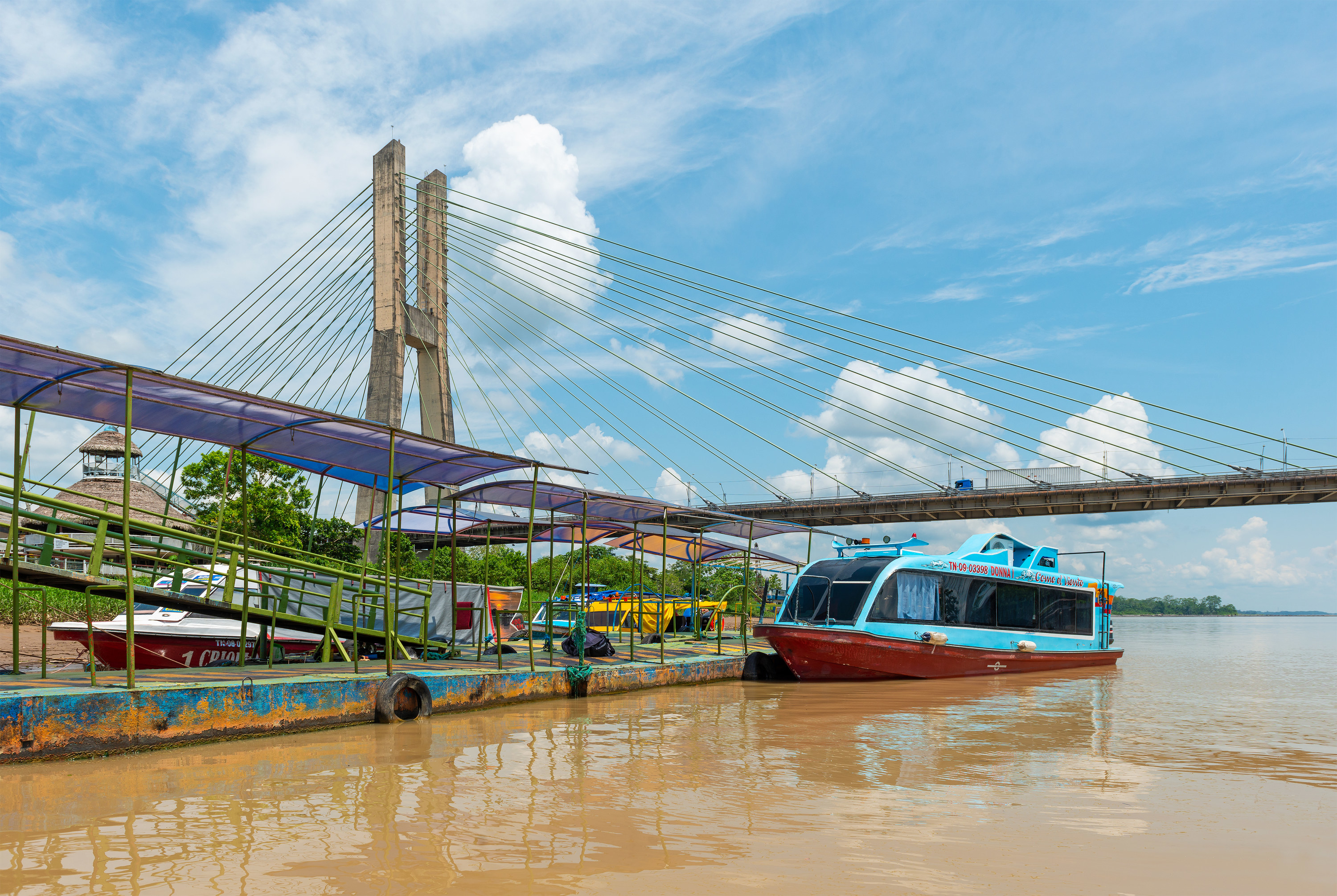 Suspension bridge over a river with a tourist boat docked