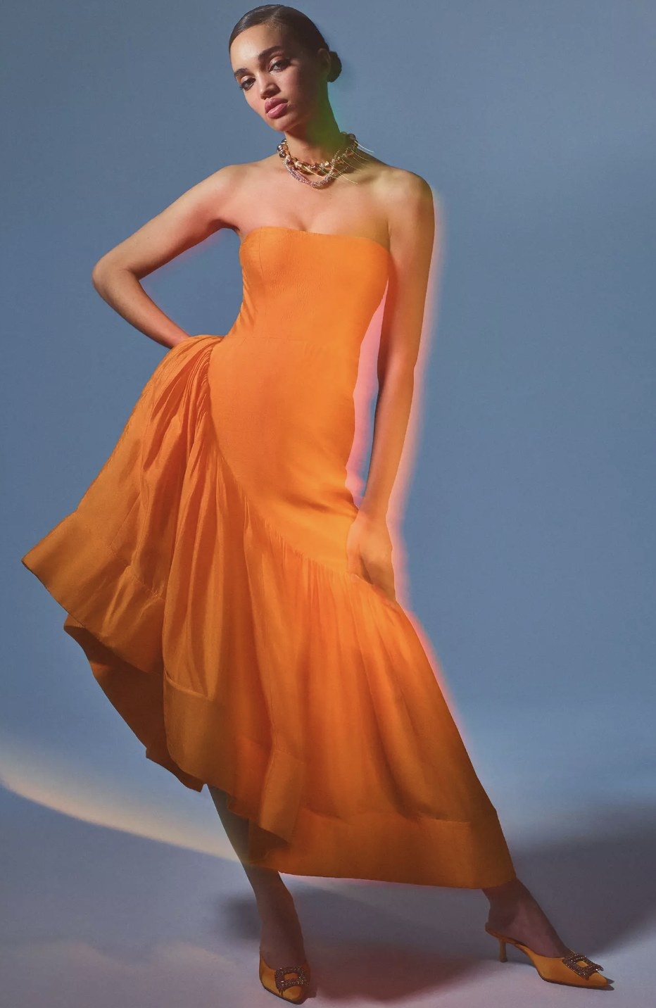 model wearing asymmetrical orange maxi dress with ruffle design
