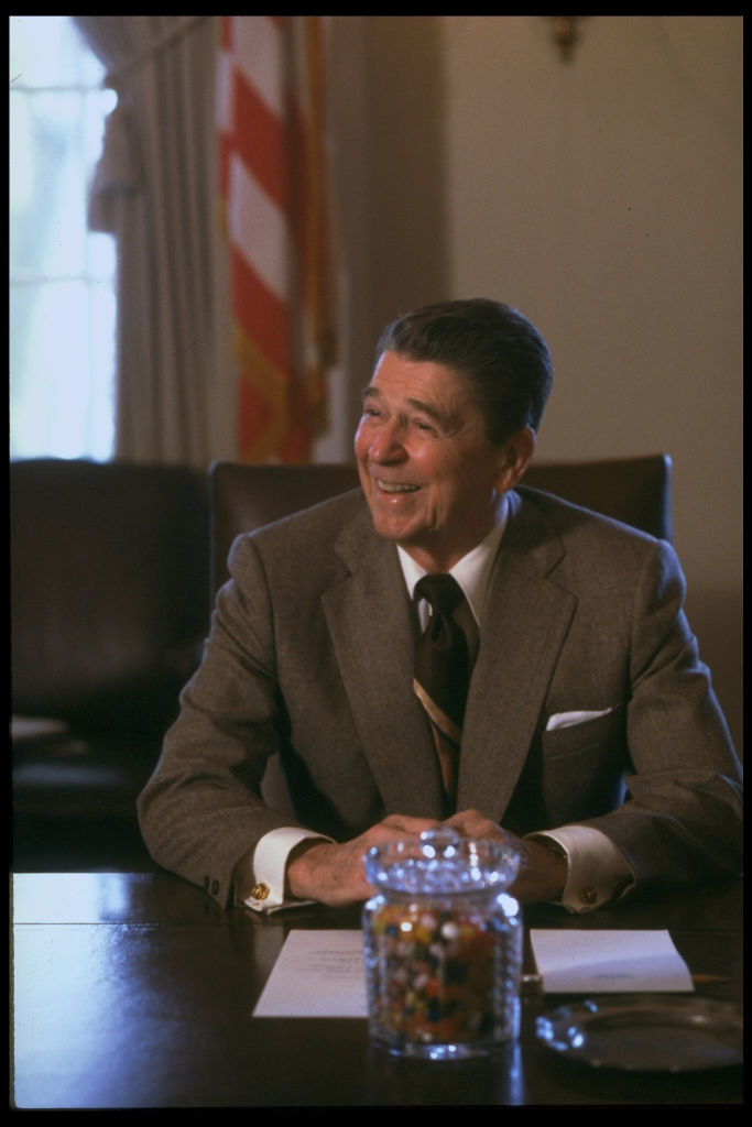 Reagan smiling at a desk with a jar of jelly beans in front of him