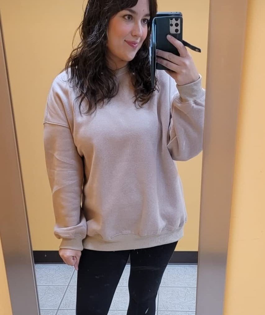reviewer wearing an oversized light gray sweatshirt and black leggings