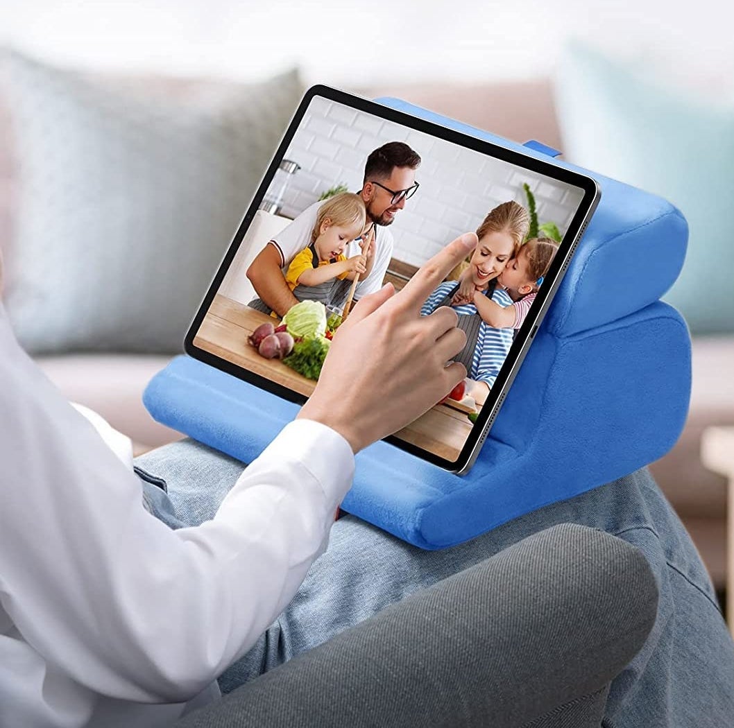 A person using an iPad on the pillow