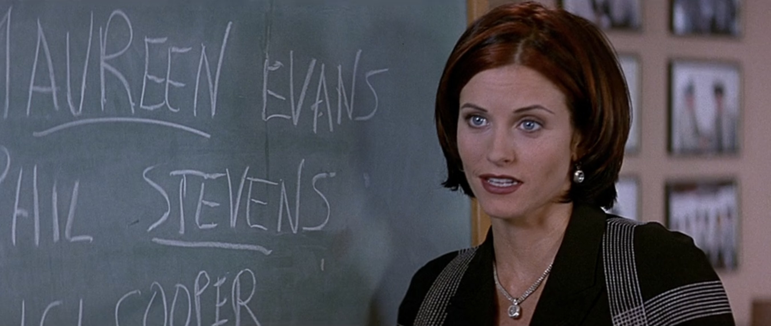 gale with a chalkboard that says maureen evans phil stevens and cici cooper in scream 2