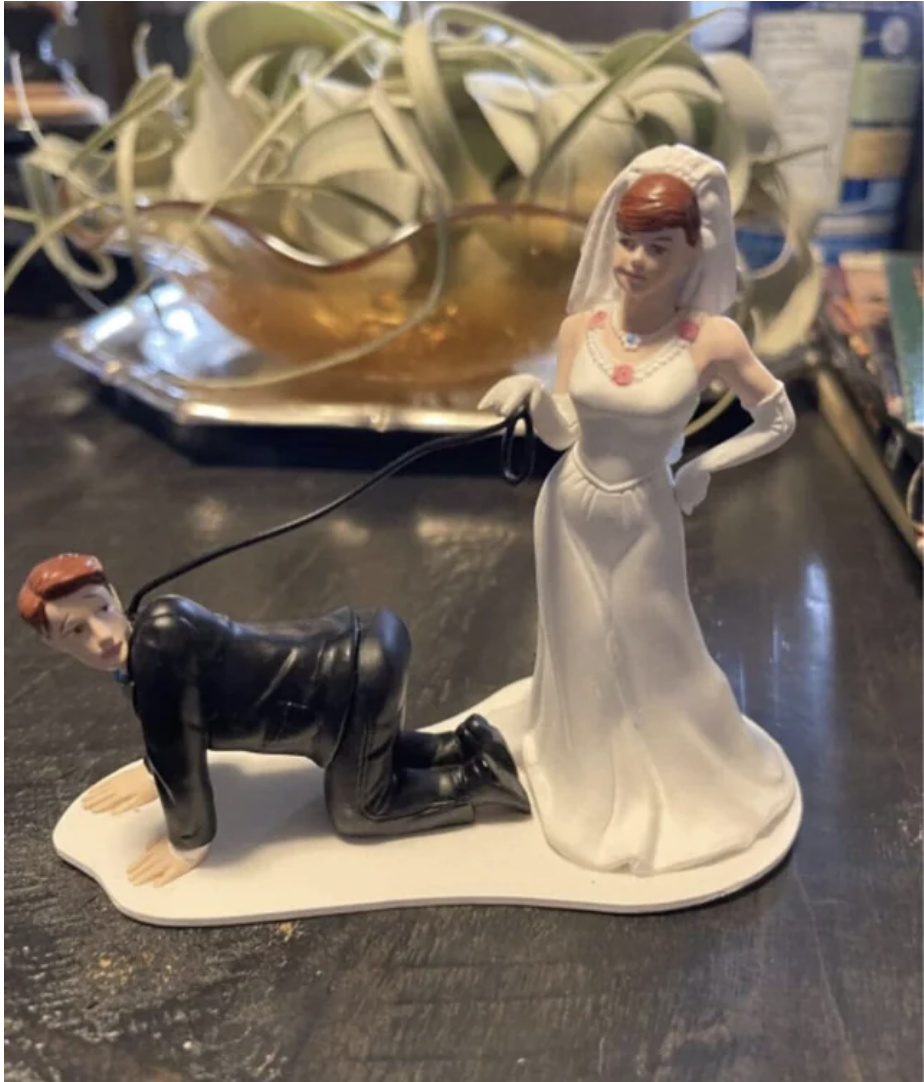 Wedding cake toppers of a bride with the groom on a leash