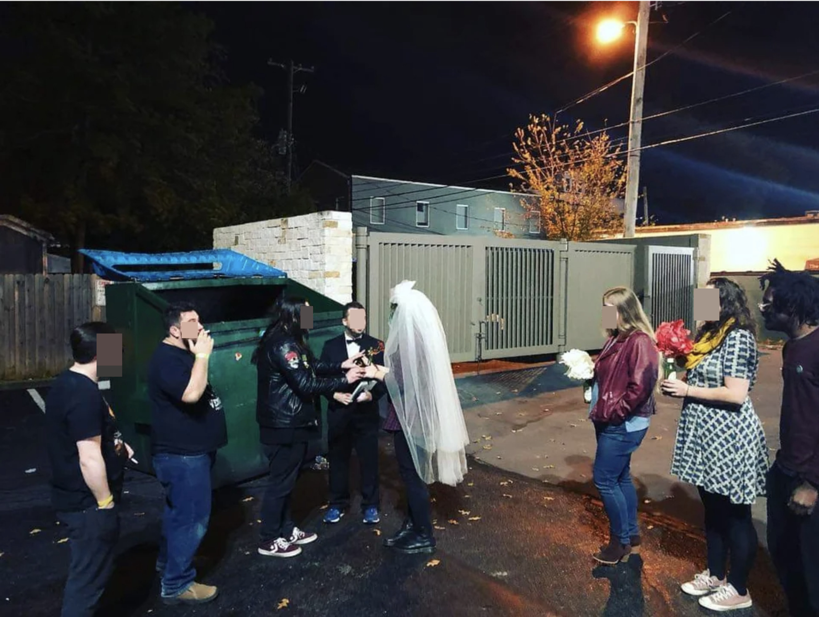 A wedding in an alley next to a dumpster