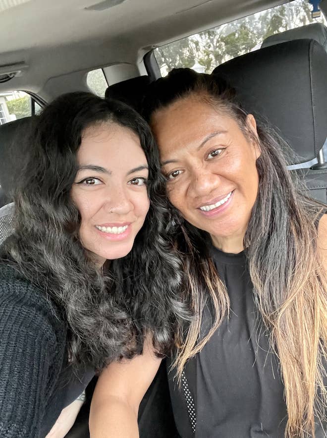 Two women in a car smiling, with heads touching