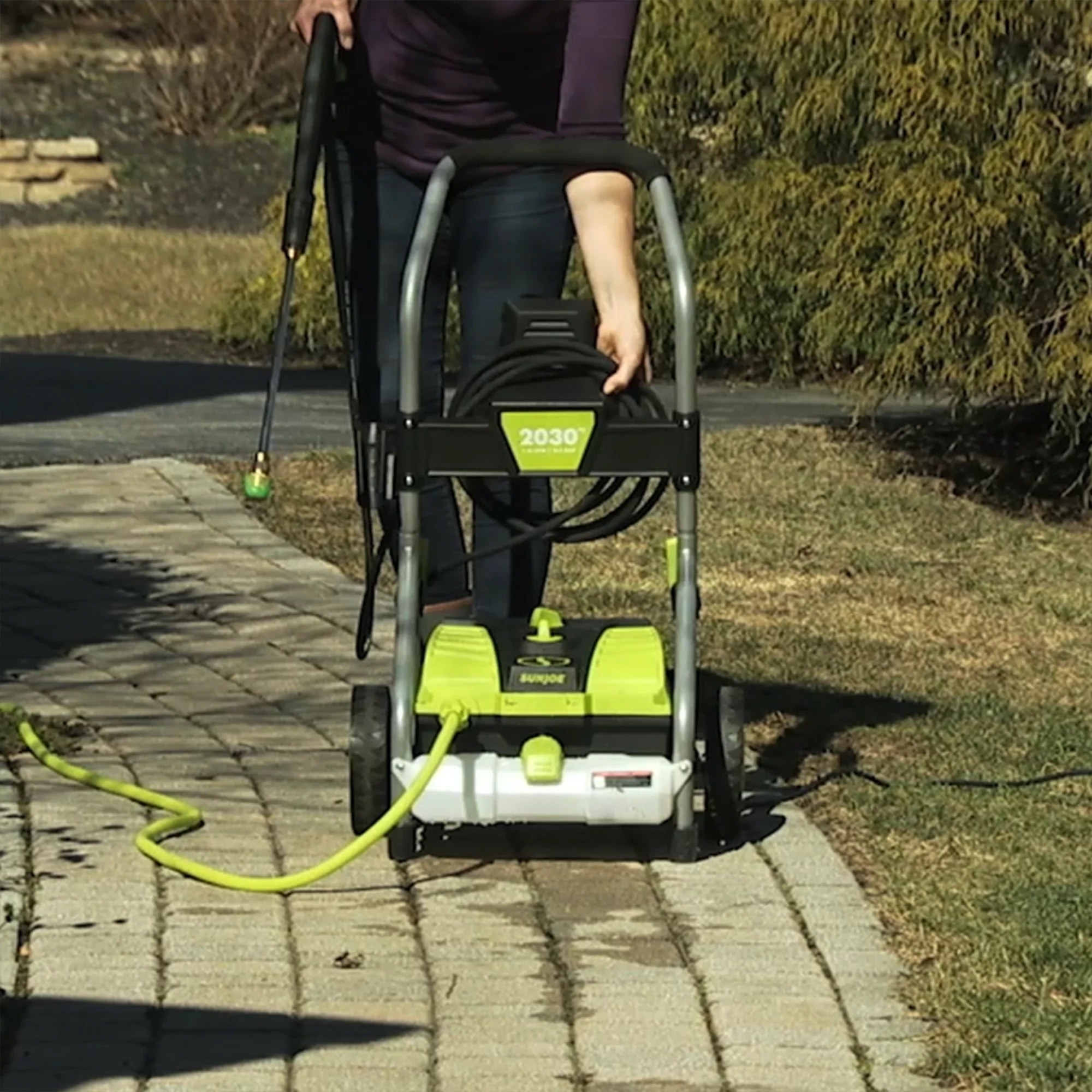 a person using a black and green pressure washer outside