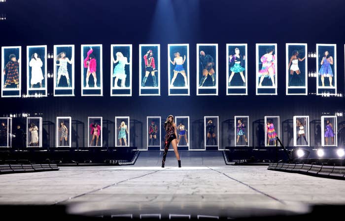 Taylor on stage with photos of her different era outfits on screen behind her