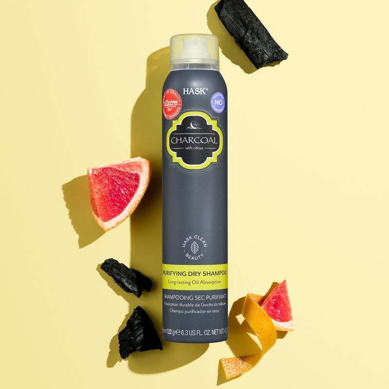 A can of dry shampoo with citrus peels, sliced fruit, and charcoal