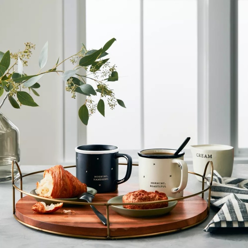 Round wooden tray with pastries and coffee mugs