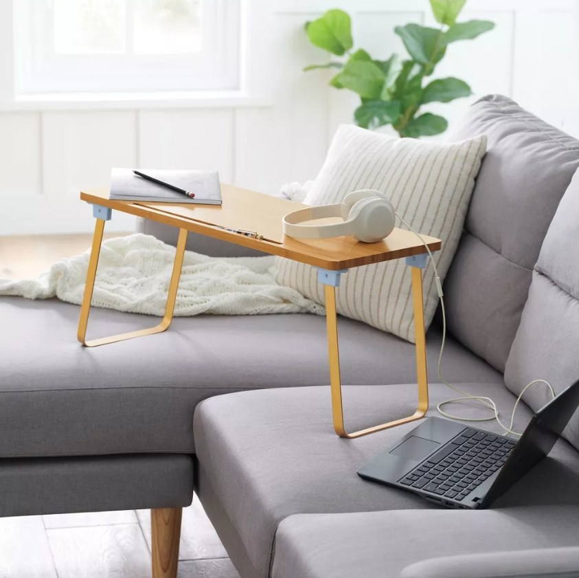 Wooden lap desk on sofa with laptop and notebook