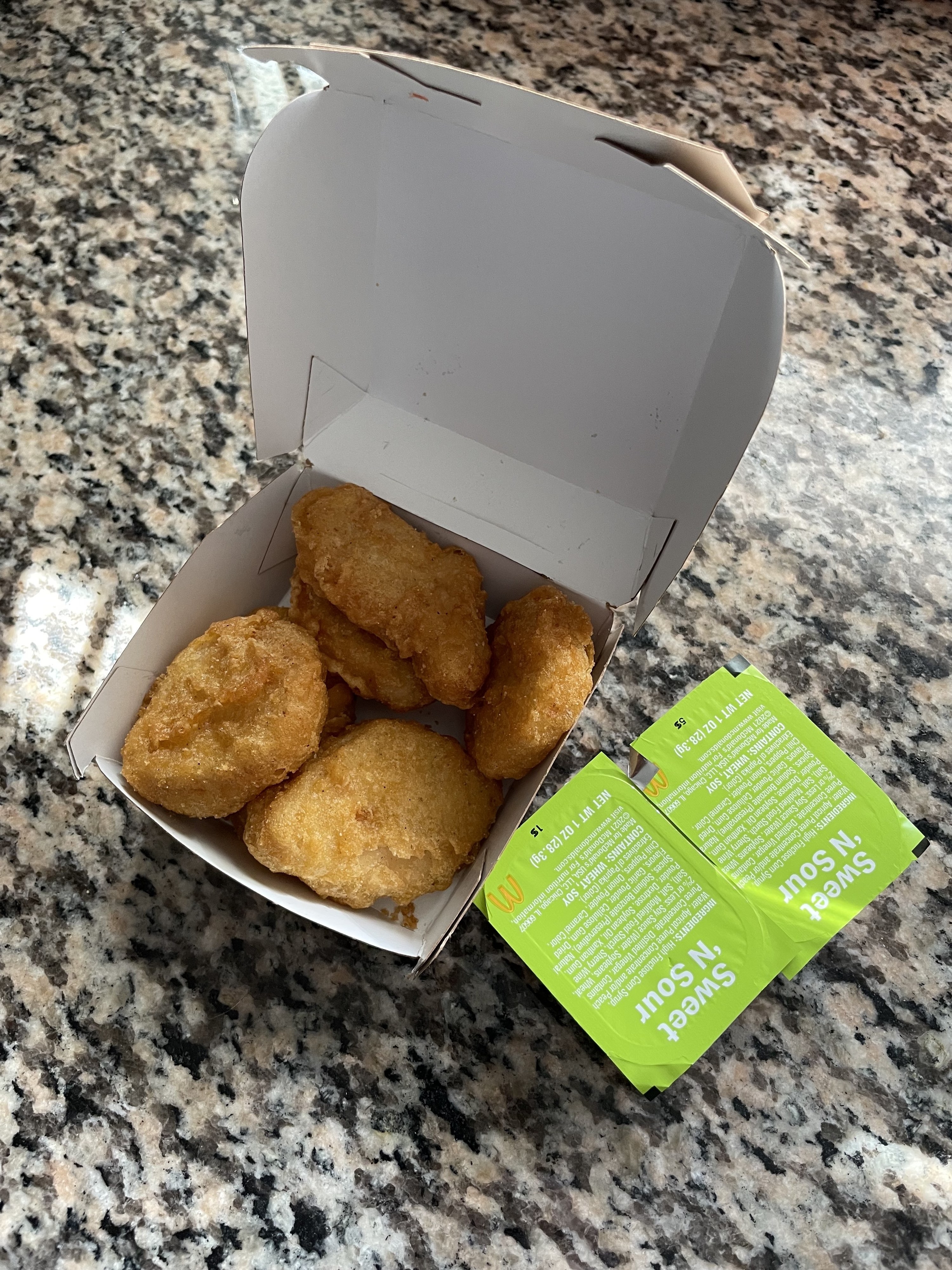 The nuggets in a takeout box with sweet &#x27;n sour sauce packets