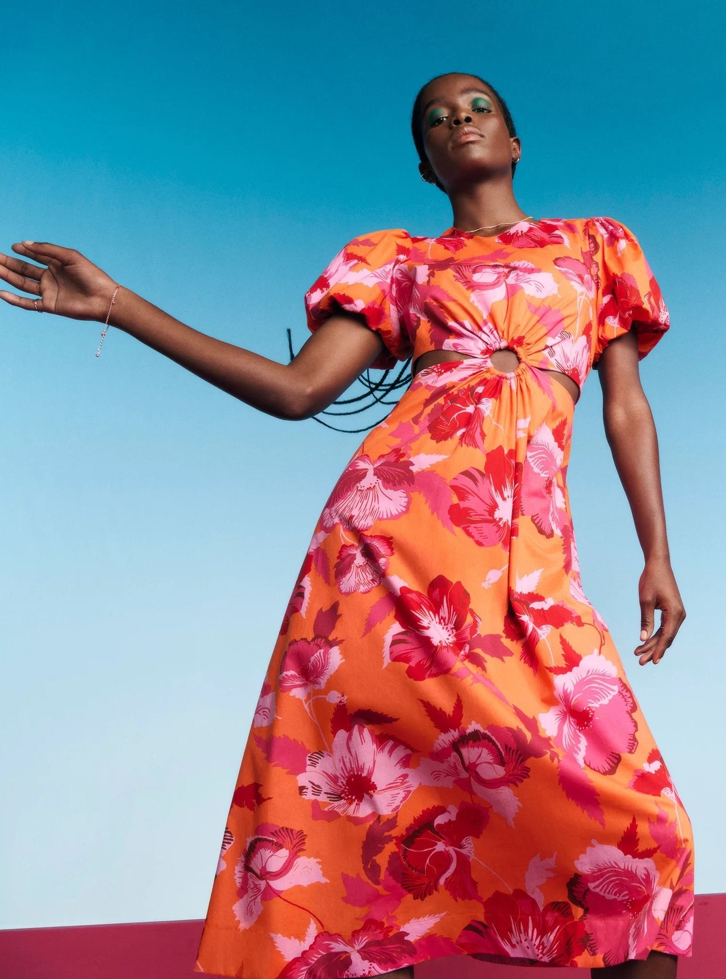Model wearing orange and pink floral dress with puff sleeves