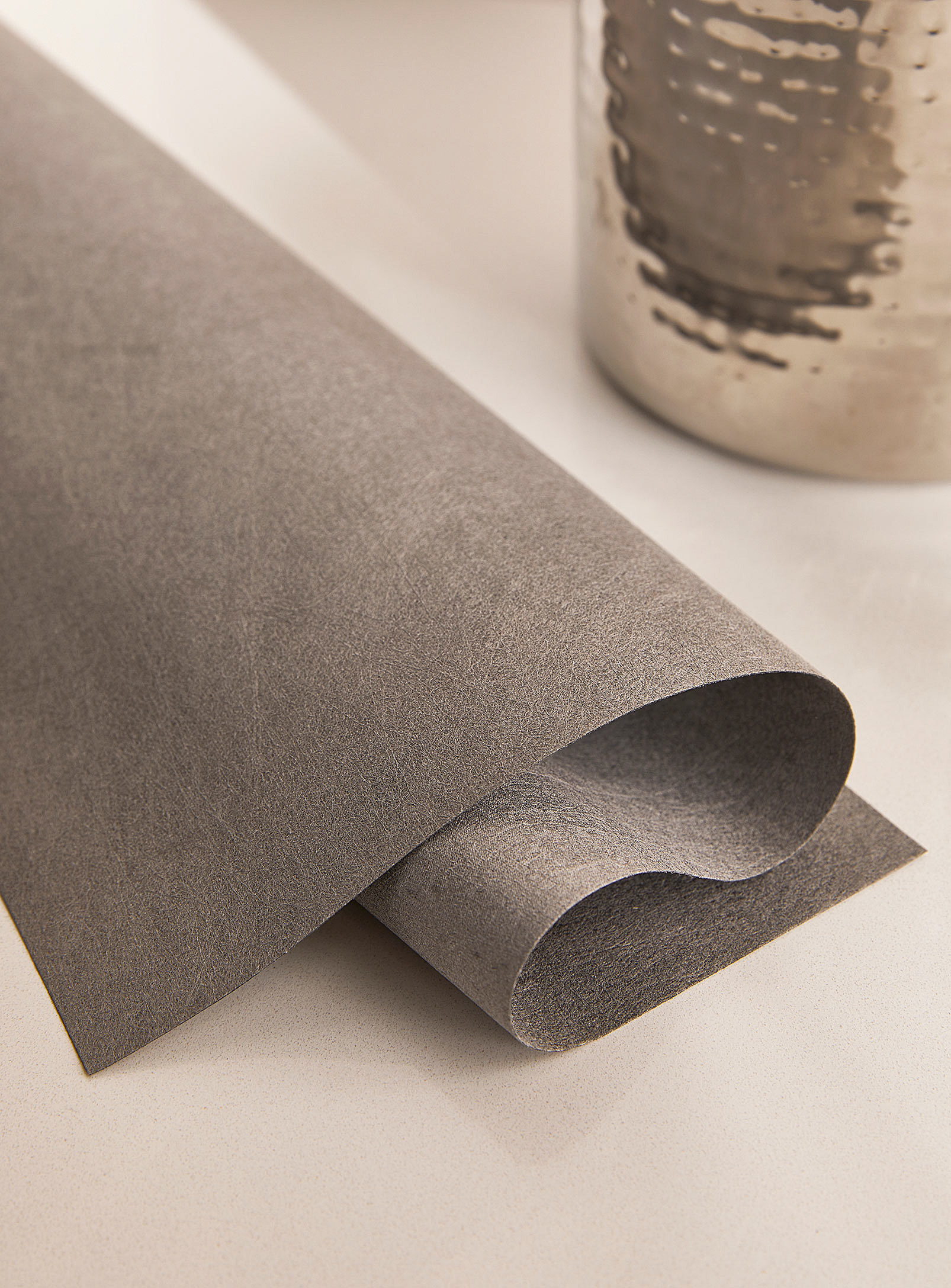 a roll of the fast-absorbing cleaning cloth next to a metallic planter