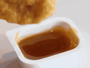 A nugget being dunked into sauce