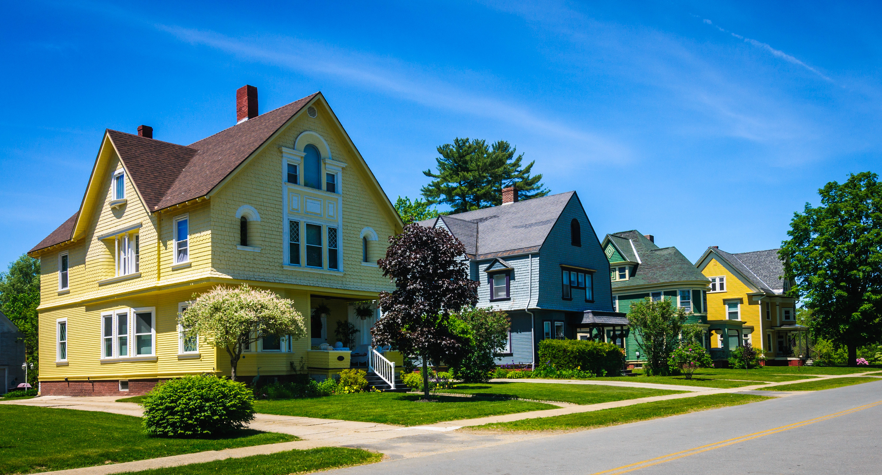 A row of well maintained, colorful, 19th century homes along a quiet street in a northern Vermont small town