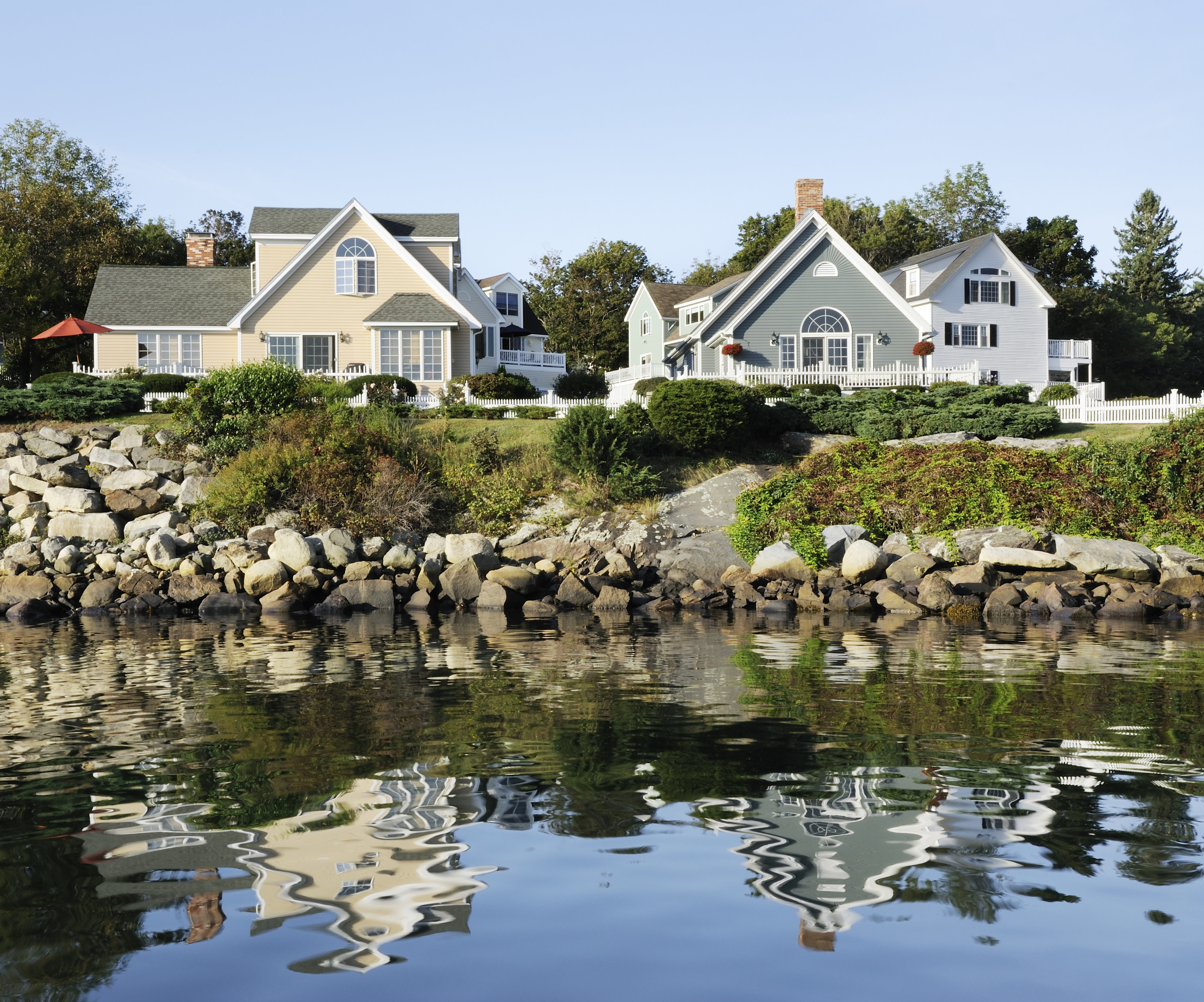 Homes on New England rocky coastline in Maine with reflection in sea water