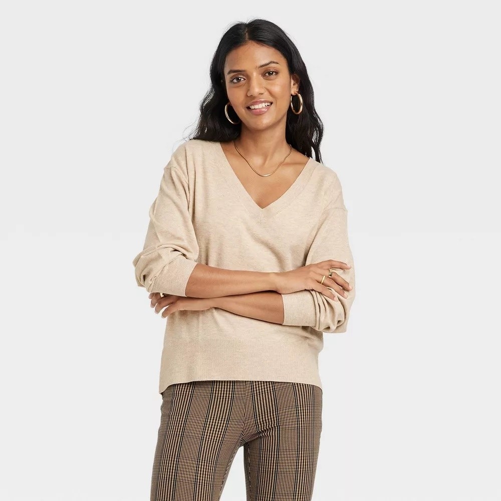 A model wearing the sweater in the oatmeal color