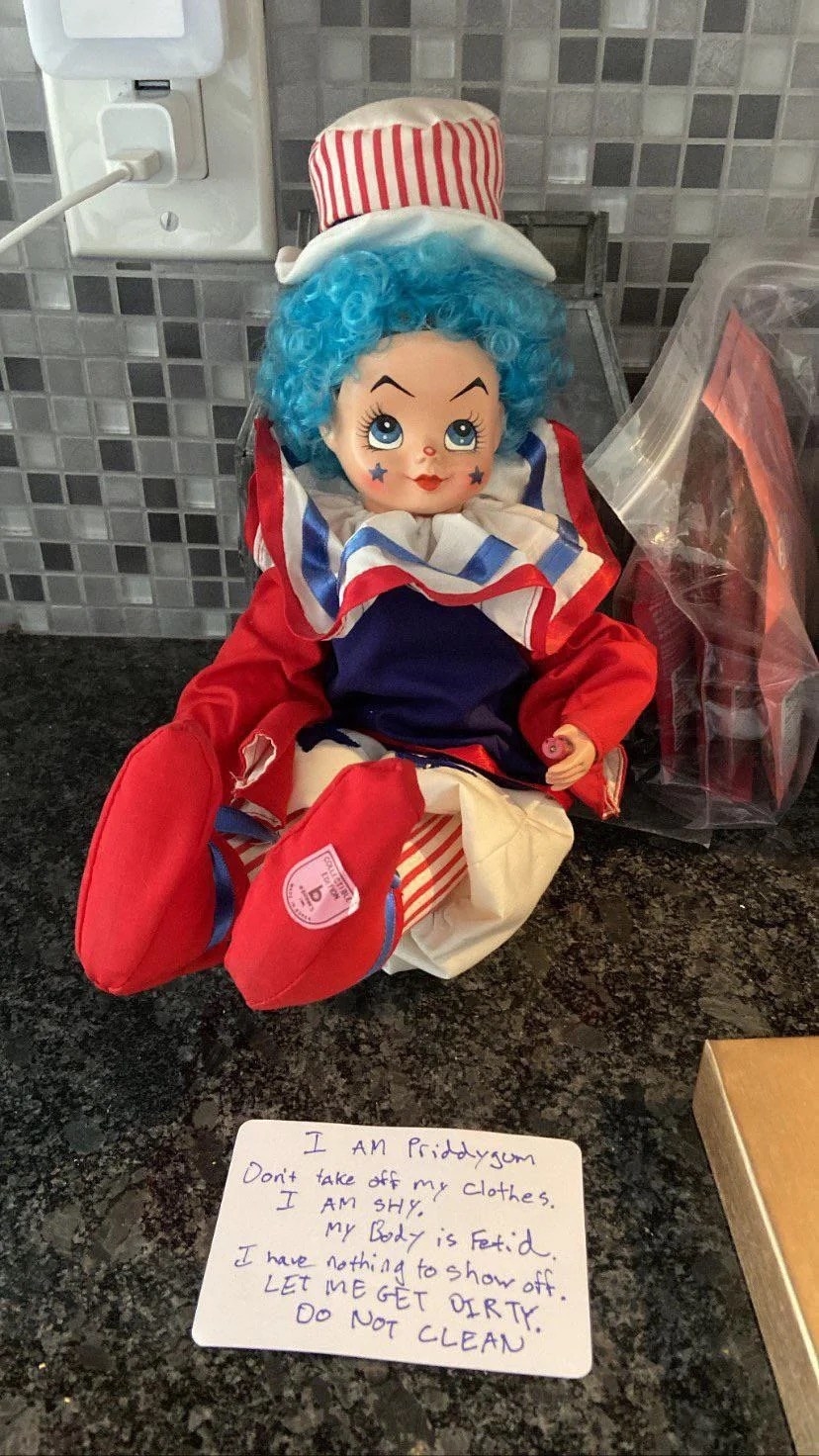 Clown in a red white and blue costume, and a note written on a card