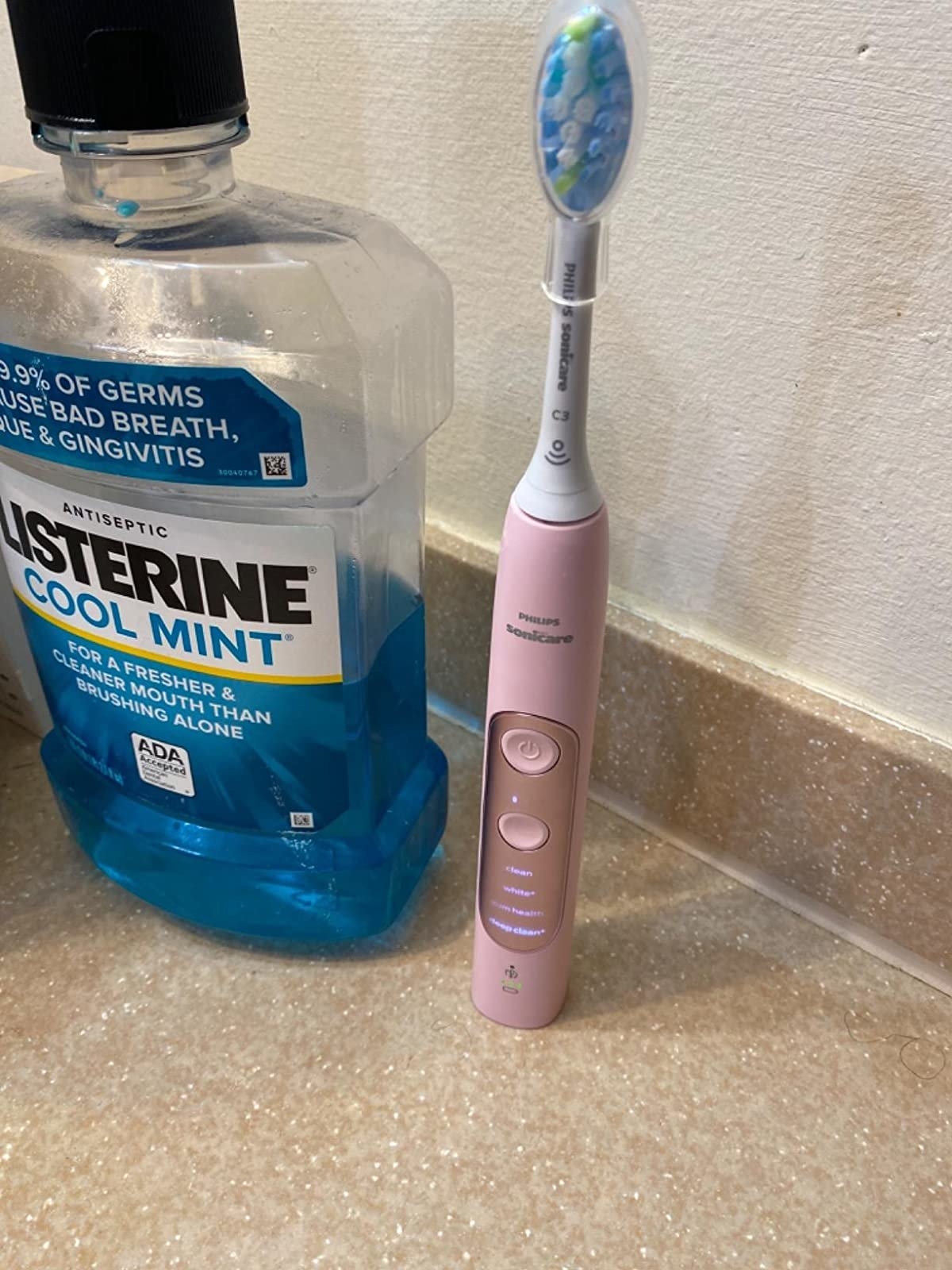 Reviewer&#x27;s pink toothbrush on counter next to mouthwash