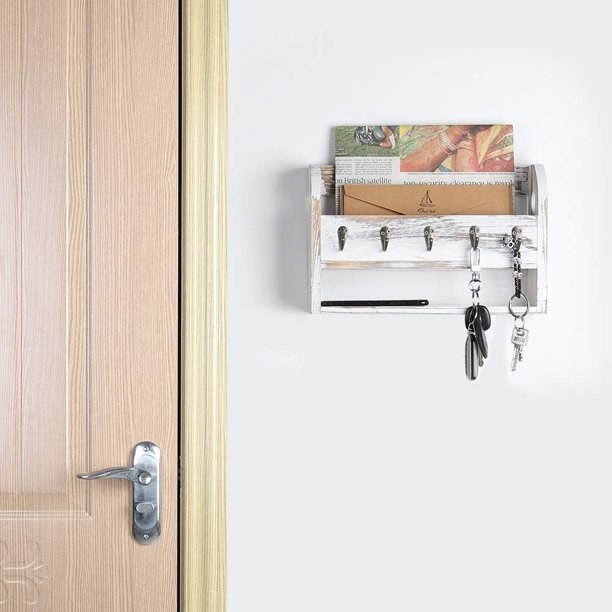 a wooden mail organizer holding letters and keys against a white wall