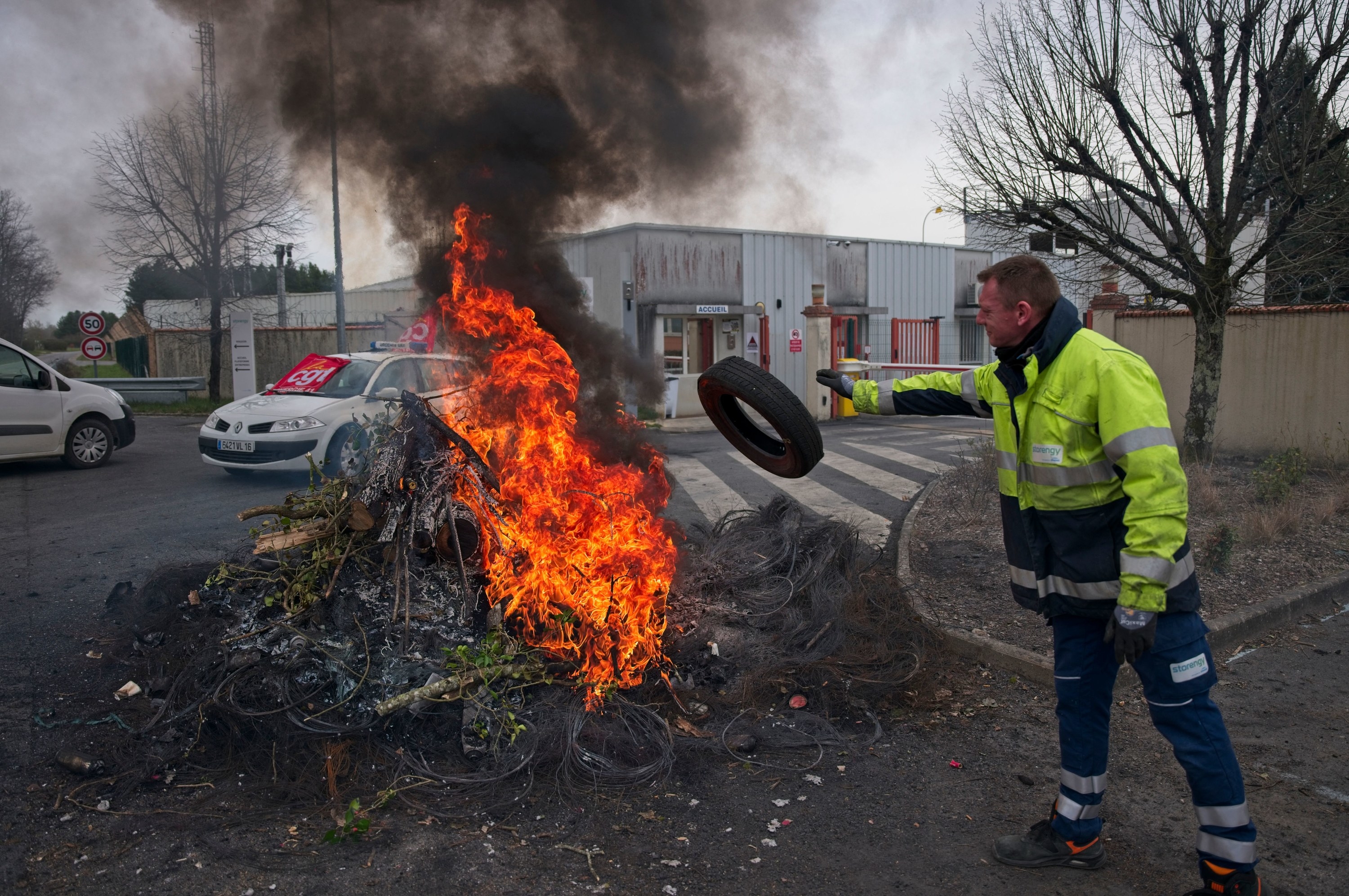 A union worker throws a tire into a burning pile