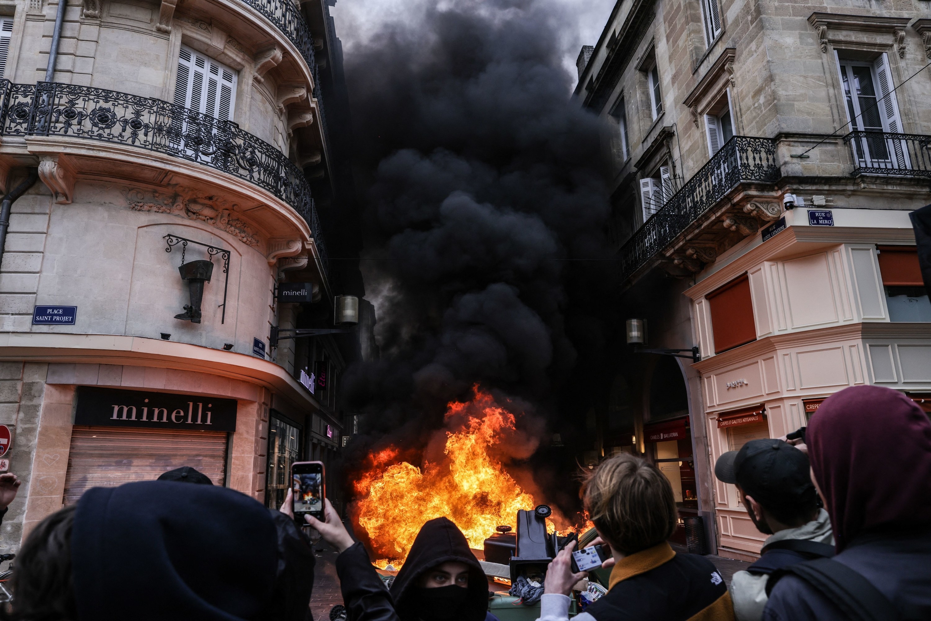 Protesters watch as a four-story-high fire burns between two buildings