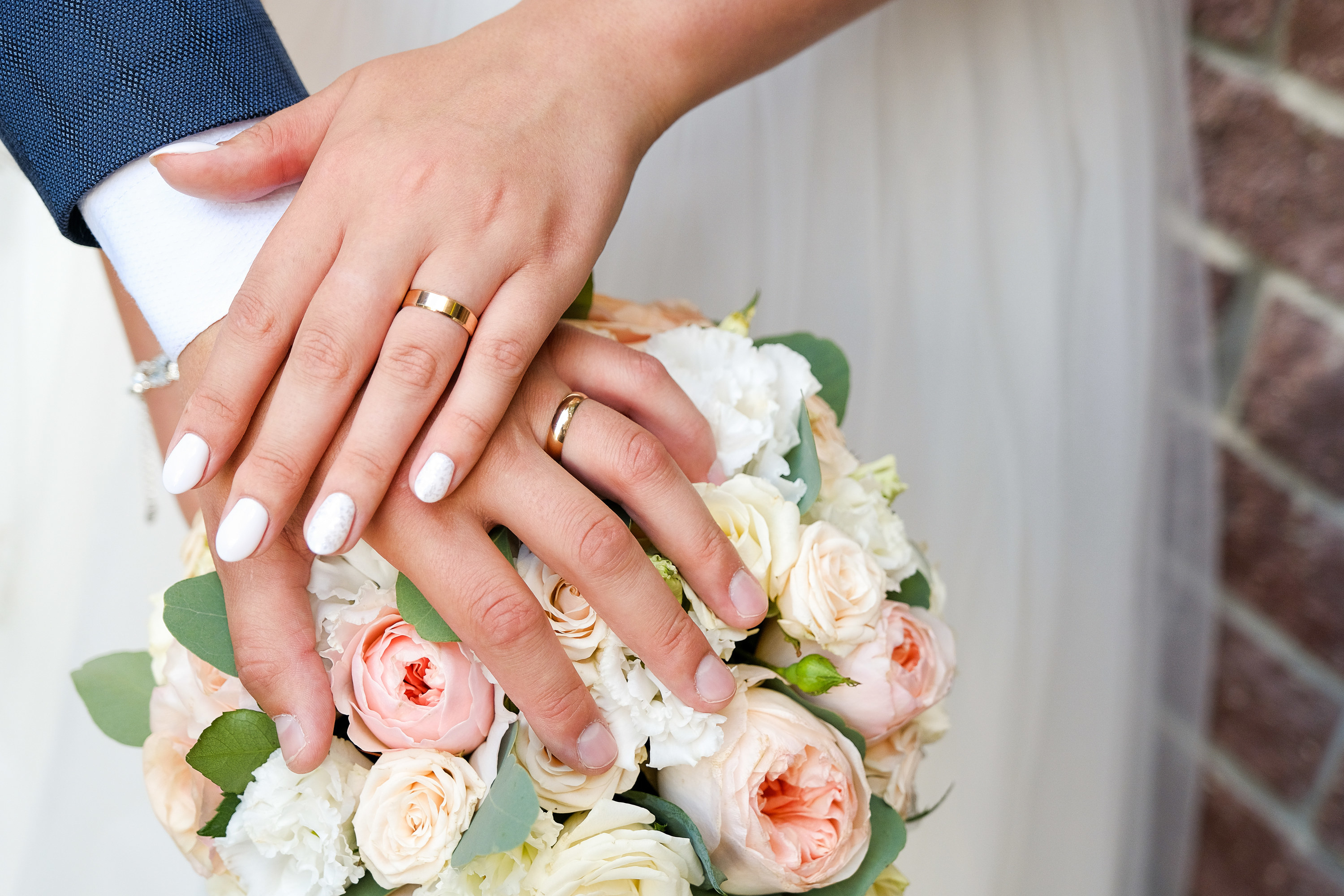 Hands of the bride and groom on the wedding bouquet.