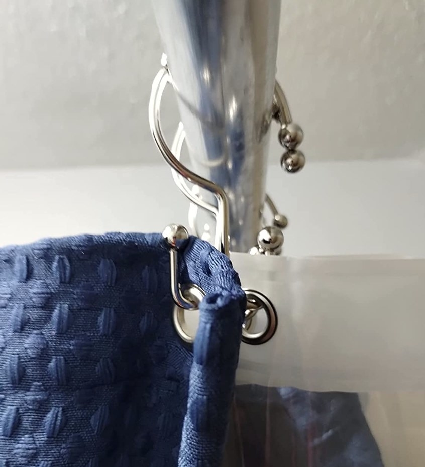 A shower curtain and liner hanging from the rings