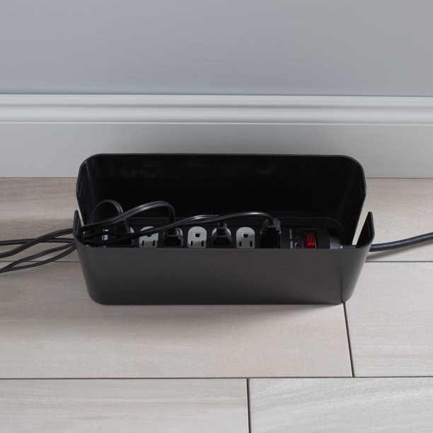 a black wire storage box holding a few wires