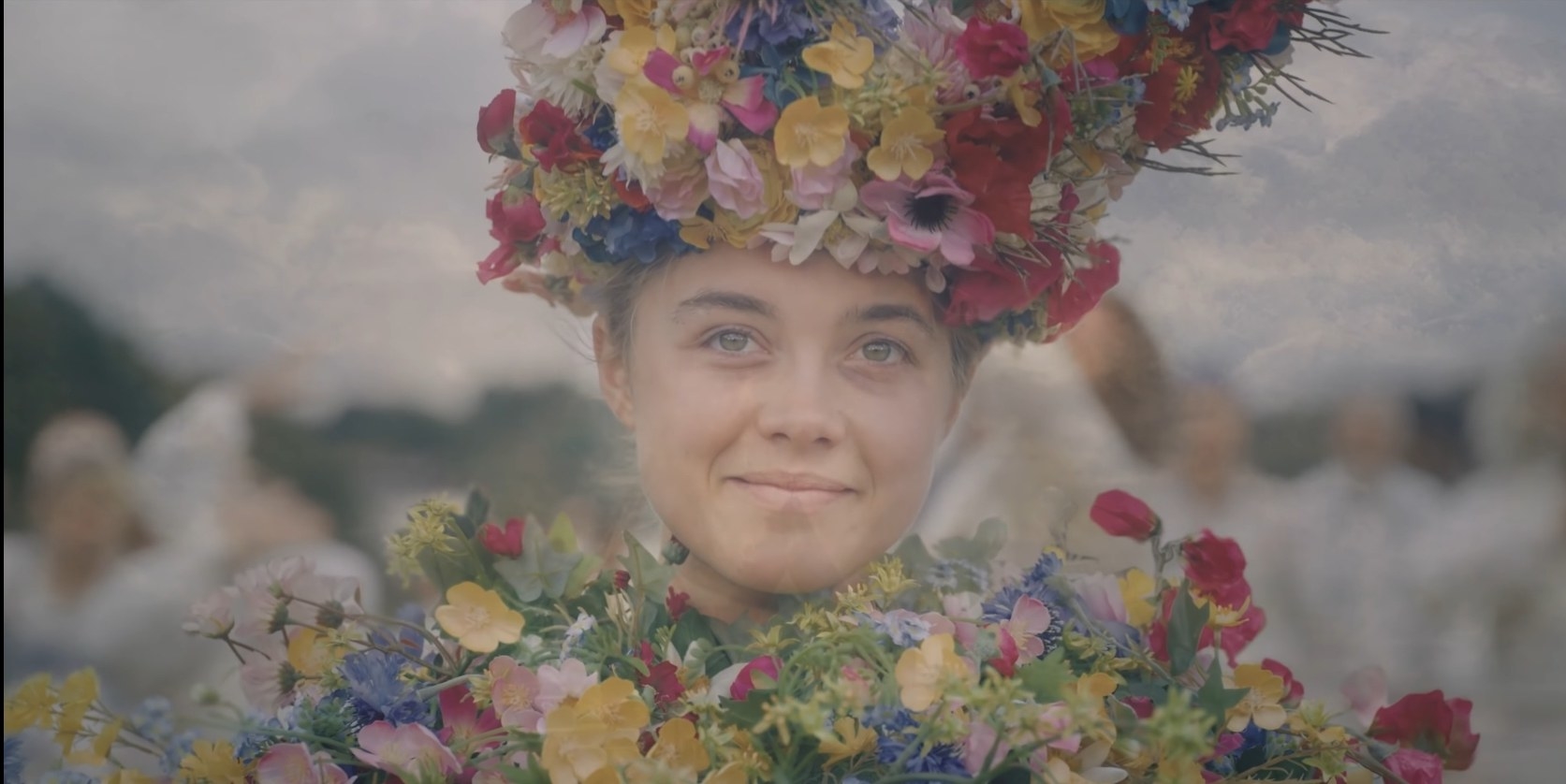 A smiling Florence Pugh sits in an ornate costume full of flowers