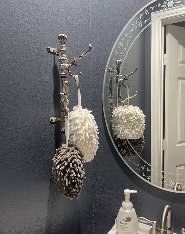 The towel balls hanging next to a bathroom mirror