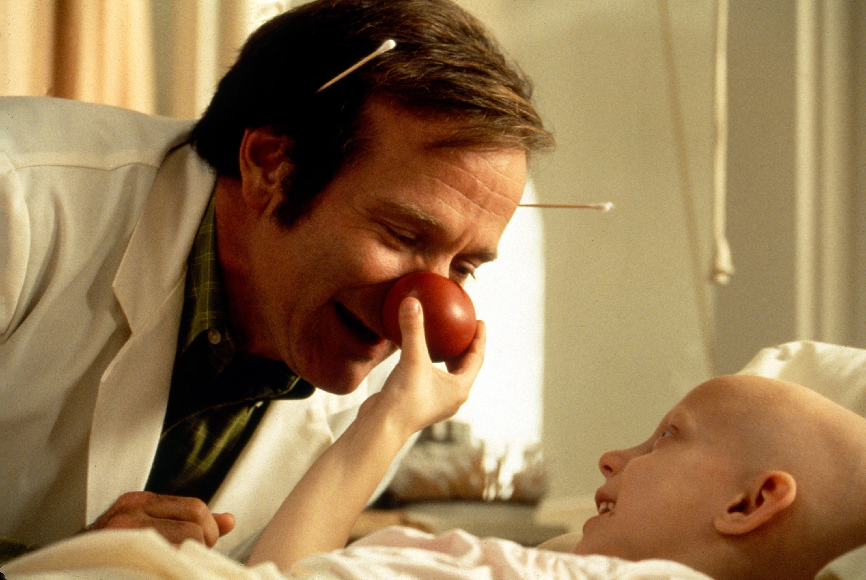 A man with a clown nose tends to a patient