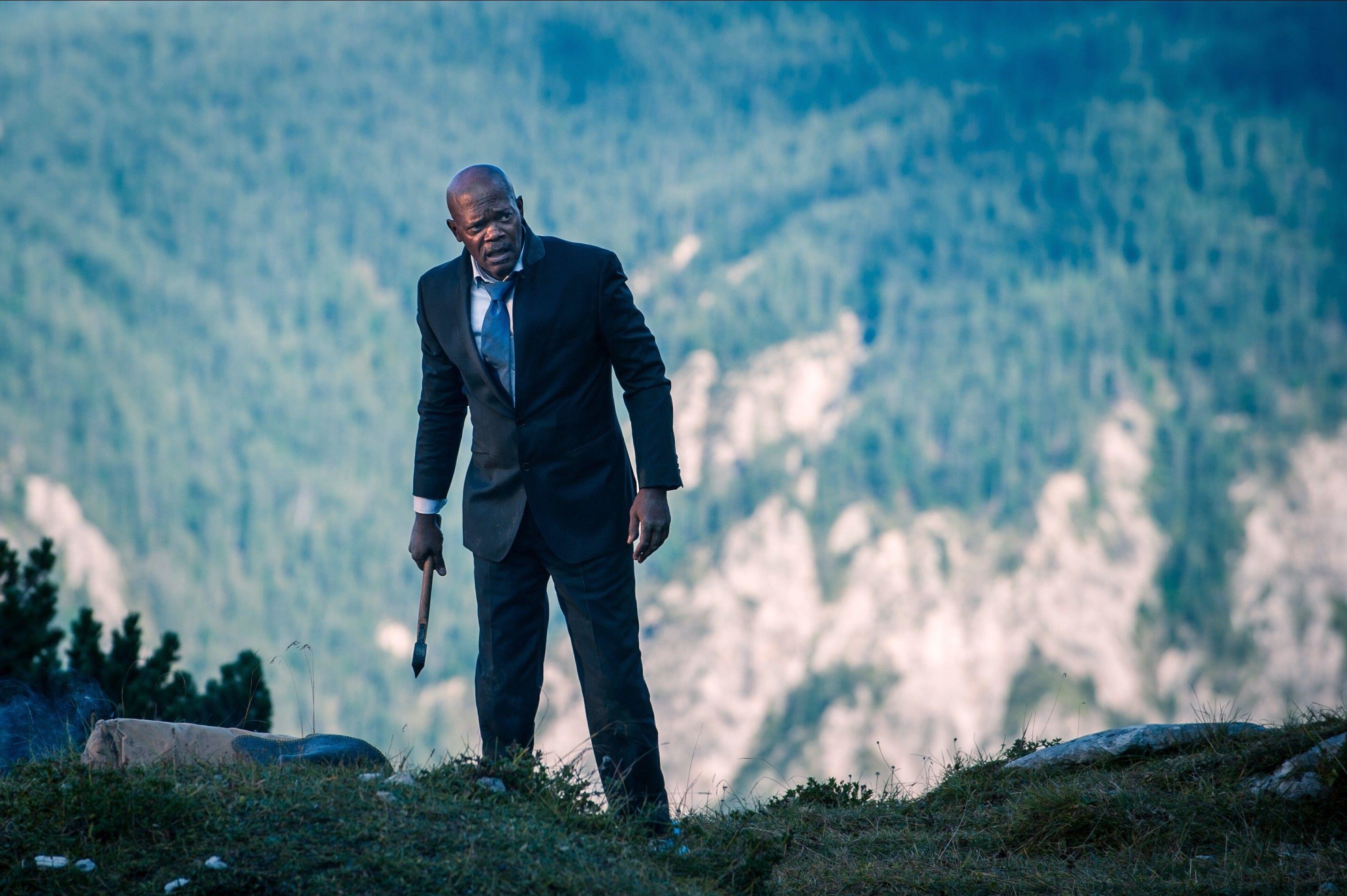 Samuel L. Jackson stands atop a mountain with a hatchet