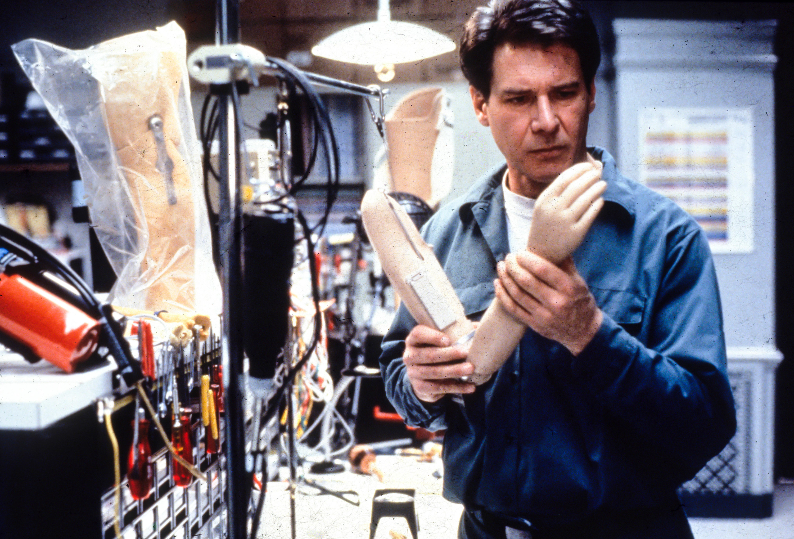 Harrison Ford examines a protesthetic arm in a laboratory