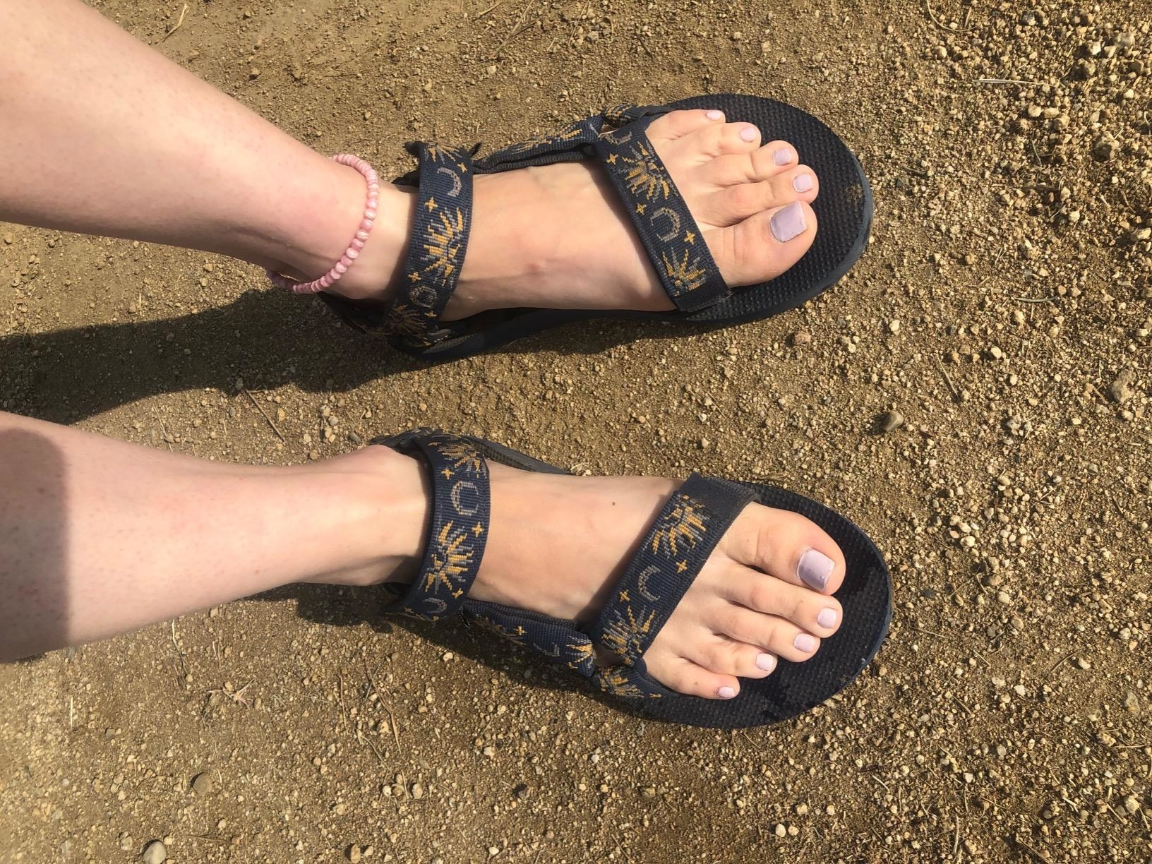 Reviewer wearing black tevas with sun and moon design on straps