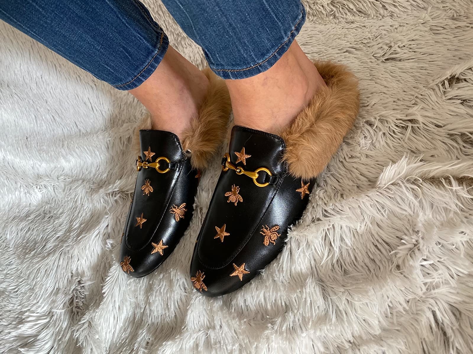 Reviewer wearing black loafer with brown embroidery design and fur heel