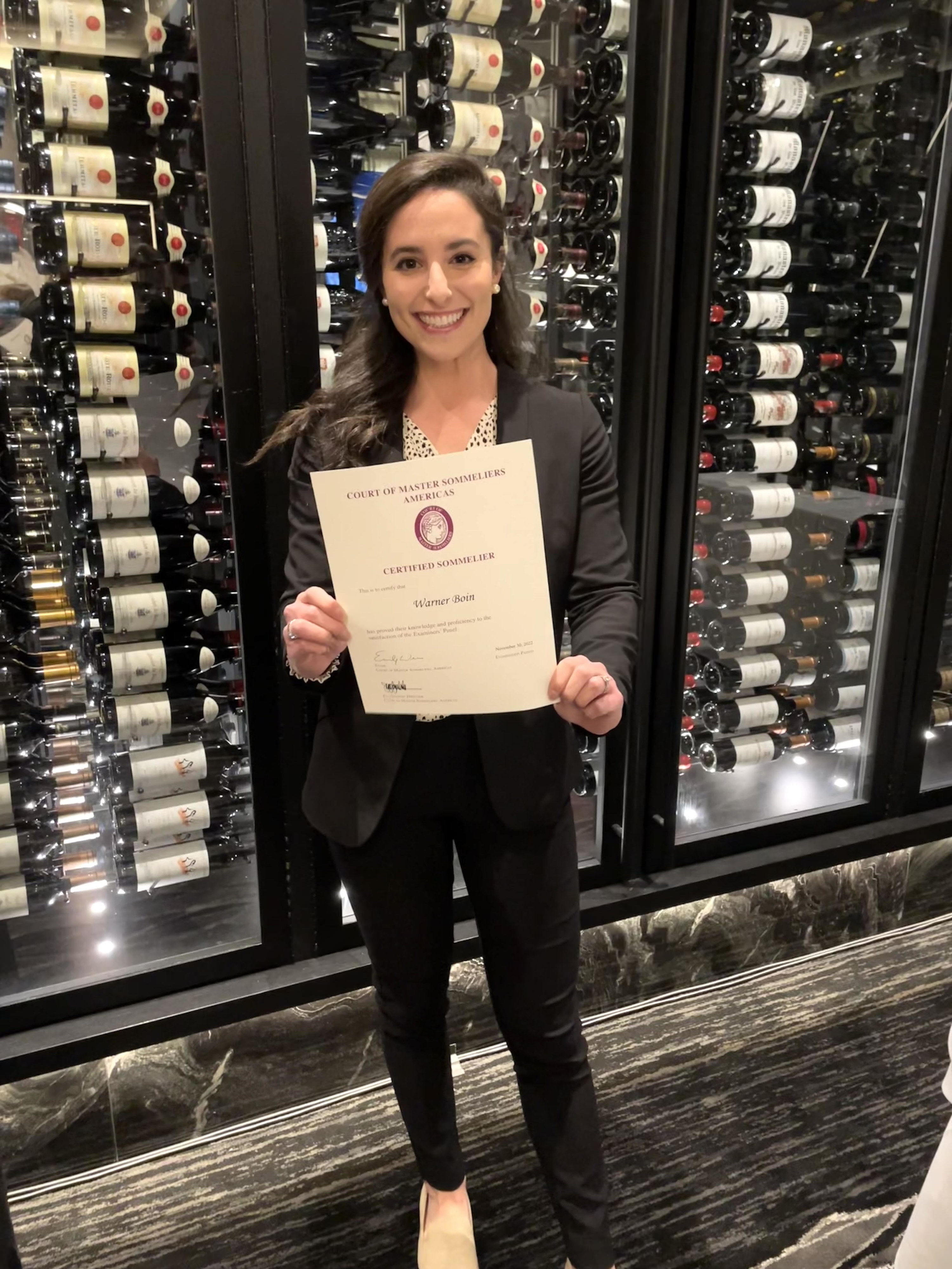 Warner holding her certificate after passing the sommelier exam