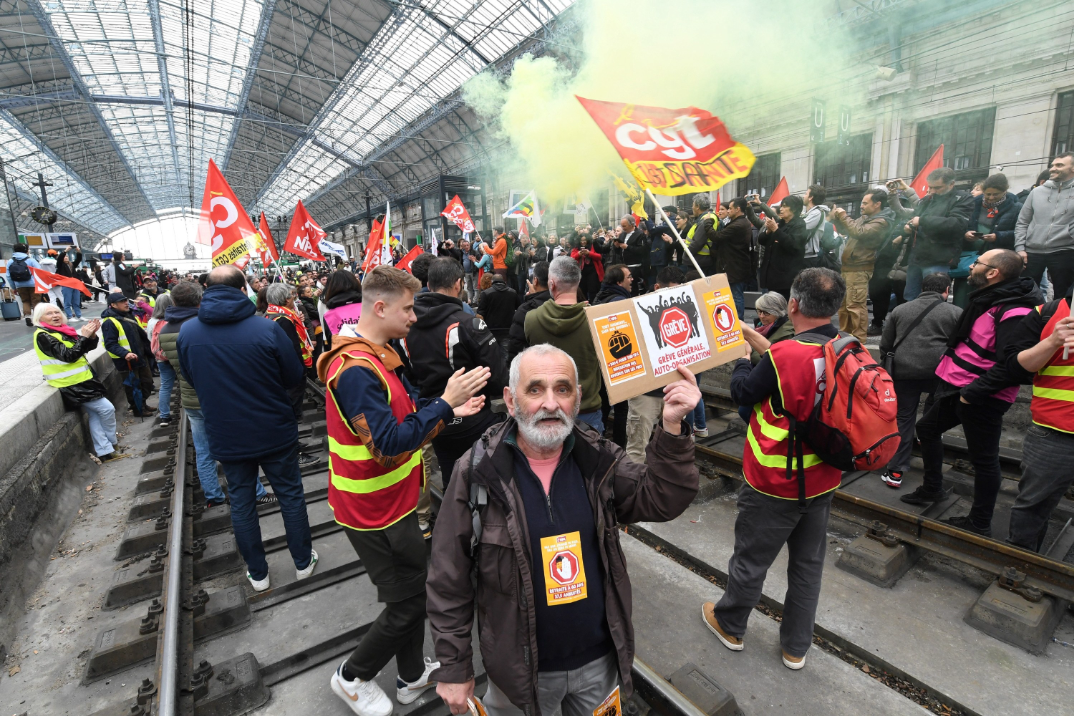 a crowd of protesters stand in a railway station