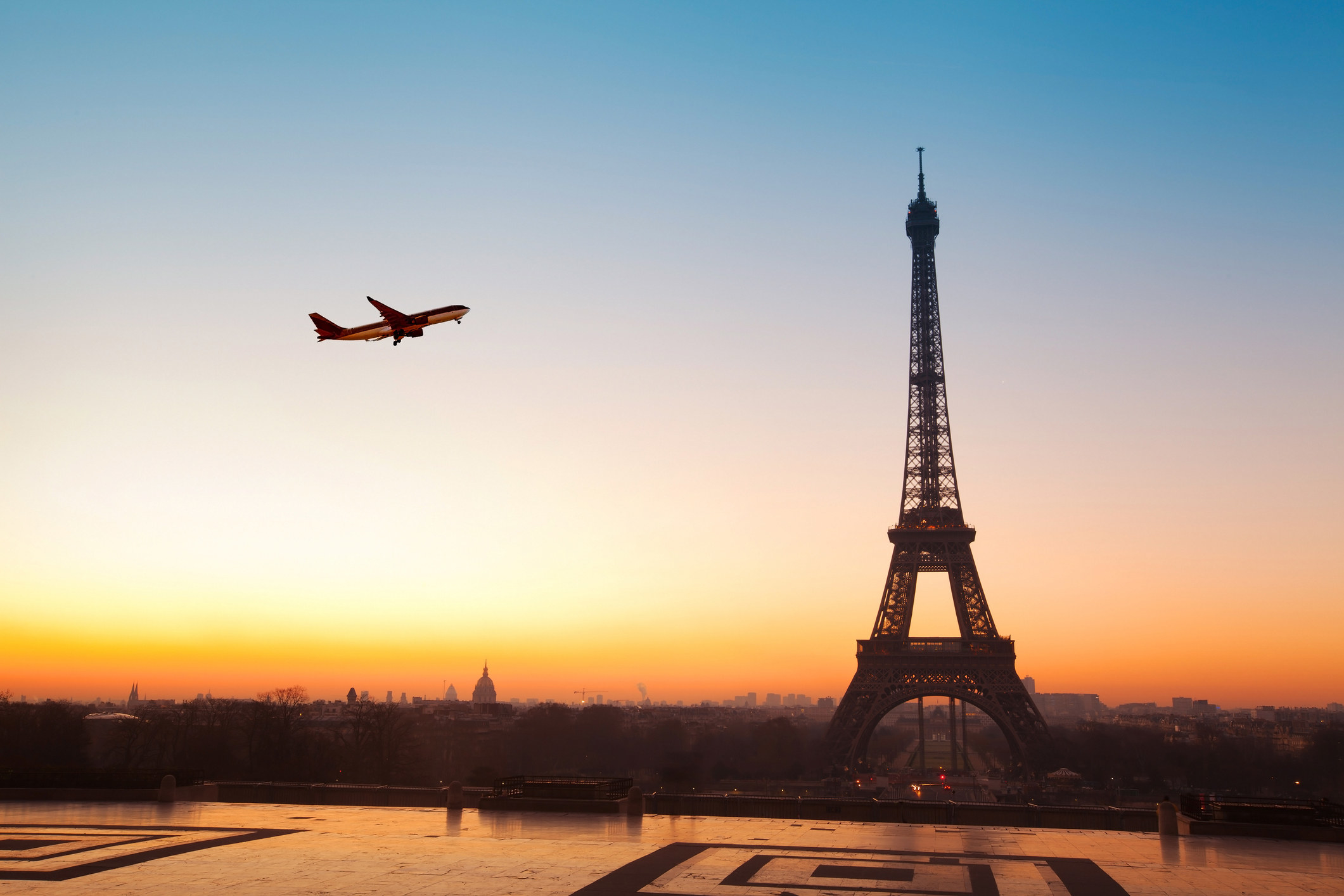 Eiffel tower at sunrise and airplane in the blue sky